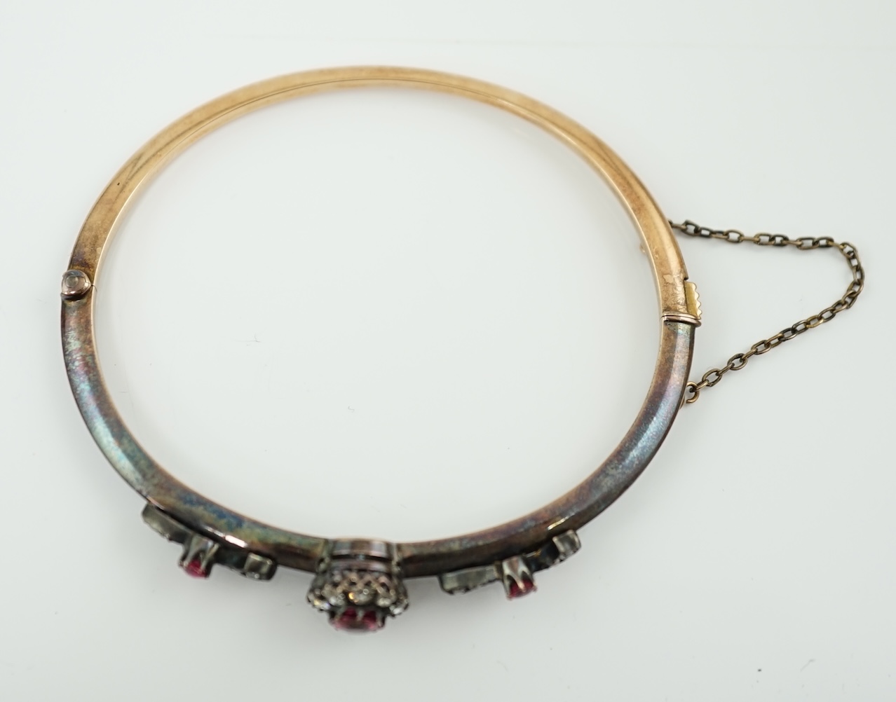 A late Victorian gold and silver, ruby and diamond cluster set hinged bangle